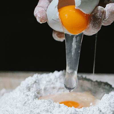 Picture of eggs being cracked over flour